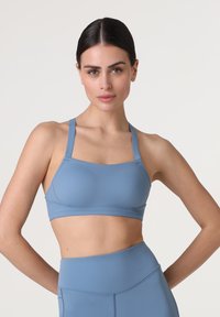 Reggiseno sportivo blu realizzato in un tessuto morbido e elastico. Presenta spalline regolabili e un design che offre supporto, adatto per l'abbigliamento attivo.
