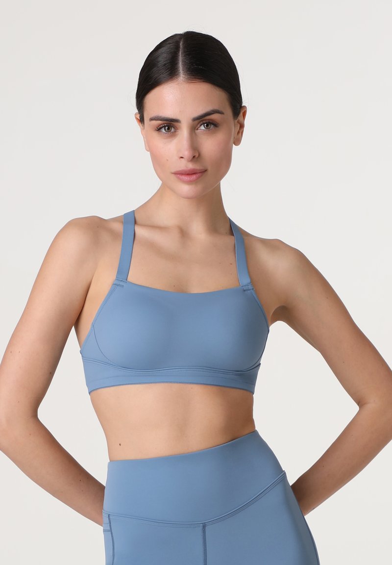 Reggiseno sportivo blu realizzato in un tessuto morbido e elastico. Presenta spalline regolabili e un design che offre supporto, adatto per l'abbigliamento attivo.