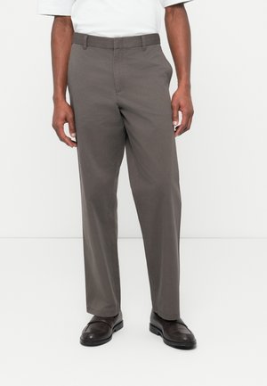 Σκούρα γκρι chino παντελόνια με ευθύ κόψιμο, κατασκευασμένα από απαλό ύφασμα, με πλαϊνές τσέπες και λεία υφή. Φοριούνται με σκούρα παπούτσια.