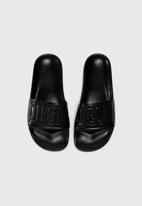 Sandales noires à glissière avec une finition brillante, dotées d'une large sangle embossée du logo "DIESEL", d'une semelle plate et d'une texture lisse.