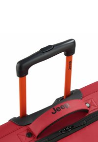 Valigia di tessuto rossa con manico nero e aste telescopiche arancioni. Presenta una chiusura con zip e un logo Jeep in evidenza sulla parte superiore.