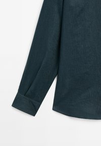 Dark teal long-sleeve shirt featuring a textured fabric, a buttoned cuff, and a slightly curved hemline.