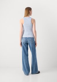 Lyseblå ribbet tanktopp kombinert med vide blå jeans. Passformen følger en avslappet silhuett, med en glatt tekstur og minimale detaljer.