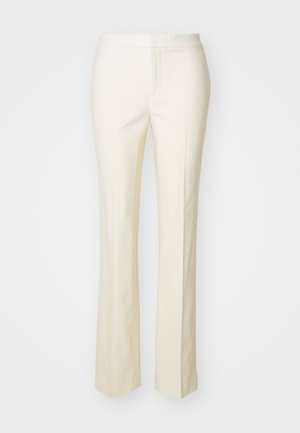 Proste kremowe spodnie o dopasowanym kroju i wyprasowanych przednich szwach, przedstawione na jednolitym białym tle.