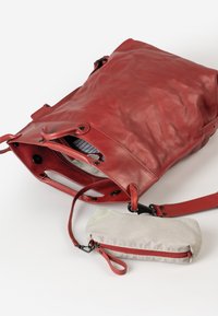 Rode leren tas met een zachte textuur en een slouchy ontwerp. Inclusief een klein gestreept tasje met een rode rits. Open bovenkant met zwarte hardware.