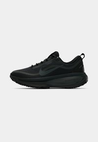 Scarpa da corsa nera Nike con design a lacci, suola spessa e ammortizzata etichettata ZoomX, e linguetta sul tallone, mostrata in profilo laterale.