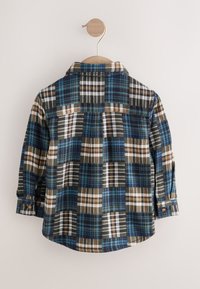 Skjorte i platternet flannel i blå, brune og beige nuancer; har krave, lange ærmer og manchetter med knapper samt en buet kant.