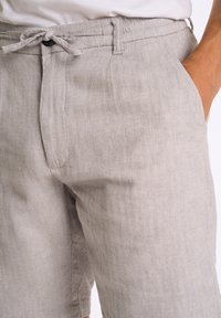 Grijze linnen shorts met een visgraatpatroon, voorzien van een elastische taille met trekkoord, zijzakken en een ontspannen pasvorm. Zacht, textuurstof.