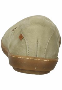 Beżowe zamszowe buty wsuwane z zaokrąglonym tyłem, widocznymi szwami i brązową gumową podeszwą. Zawiera mały skórzany akcent w pobliżu pięty.