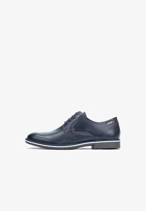 Dunkelblaue Lederschuhe mit glatter Oberfläche, ausgestattet mit fünf Ösen, kontrastierenden Nähten und einer weißen Gummisohle mit schwarzem Rand.