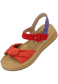 Sandal de colores múltiples con un detalle de nudo en gamuza roja, correa para el tobillo morada y una suela acolchada en tono marrón claro con un agarre texturizado.