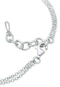 Silverfärgad kedjearmband med ovala länkar, en krabbklämma och flera trådar för textur. Slät metallfinish med glänsande yta.