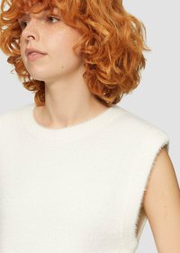 Haut sans manches blanc en tissu doux et texturé. L'encolure est arrondie et légèrement duveteuse, avec des bords bruts aux emmanchures.