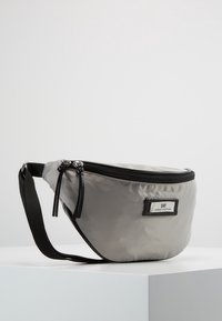 Szary nylonowy nerkowiec z czarnym zamkiem błyskawicznym, regulowanym paskiem i prostokątną metką oznaczoną "DAY" z przodu. Gładka faktura.