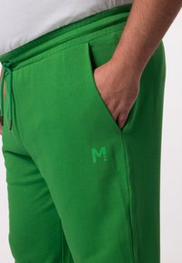 Groene katoen joggers met een elastische tailleband en aantrekkoord, voorzien van een zijzak en een subtiele logo-opdruk op de stof.