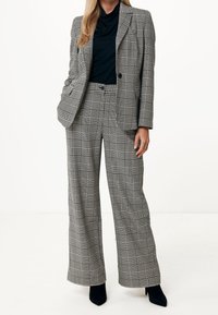 Schwarz-weiß kariertes Blazer und Hose mit weitem Bein, strukturiertem Stoff und schmaler Passform, kombiniert mit einem kontrastierenden schwarzen Oberteil.