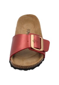 Röd lädersandal med en bred rem, prydd med en guldfärgad spänne. Fotbädd i kork och yttersula i svart gummi ger kontrast och textur.