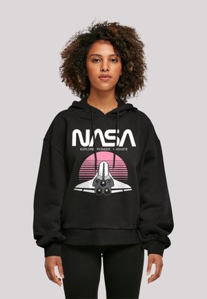 Black hooded sweatshirt featuring a front NASA logo with a space shuttle graphic, set against a pink sunburst design. Cotton blend fabric.