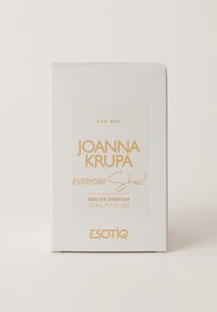 Biała pudełko na perfumy z złotym napisem. Zawiera napisy "Dla Niej", "Joanna Krupa", "Codzienny Show!" oraz szczegóły 50 mL / 1,7 FL. OZ. od Esotiq.