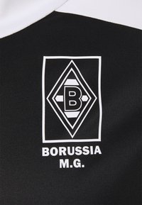 Black sports jersey with a white collar, featuring a diamond-shaped logo and text "BORUSSIA M.G." in bold white font beneath.