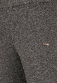 Gray knit joggers with a soft texture, featuring a subtle logo tag, elastic waistband, and tapered legs. Durable and comfortable material.