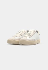 Sneakers in light cream and grey suede, featuring a smooth white leather panel, tonal laces, and a textured beige rubber sole.