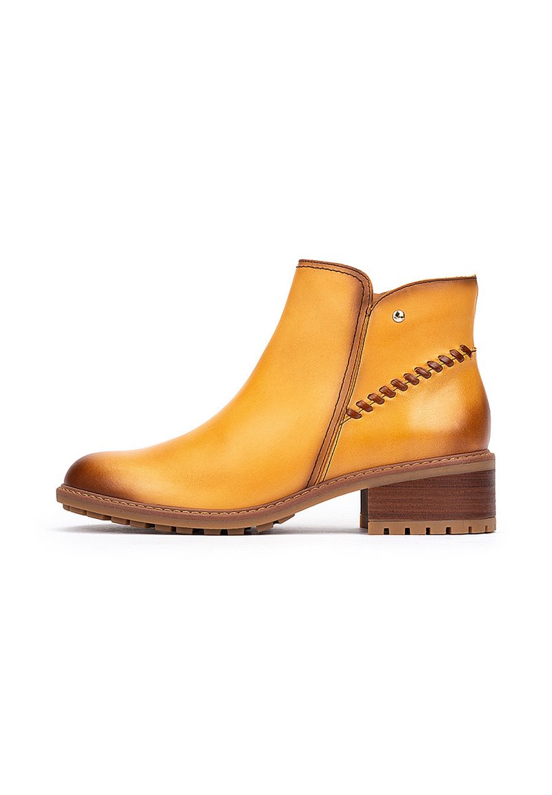 Botas de cuero de tobillo en color mostaza, con una punta redondeada, detalles de costura en el costado y un tacón bajo tipo bloque con una suela texturizada.