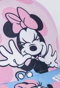 Casquette de baseball en tissu rose et bleu affichant un personnage de dessin animé. Présente un grand graphique d'un personnage souriant avec un nœud et des pois.