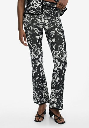 Black and white patterned flared pants featuring a textured, abstract design, with a fitted waist and slight flare at the ankle.