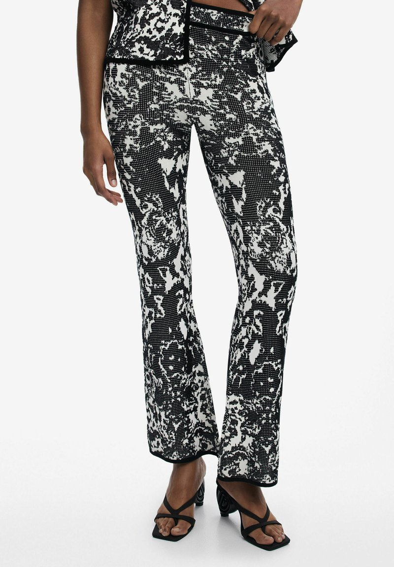 Black and white patterned flared pants featuring a textured, abstract design, with a fitted waist and slight flare at the ankle.