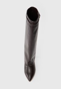 Bota de cuero marrón hasta la rodilla con punta afilada, textura suave y parte superior doblada, que presenta un sutil acento de hardware dorado.