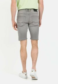 Graue Jeansshorts mit klassischer Passform, ausgestattet mit Gesäßtaschen und einem Reißverschluss, kombiniert mit weißen Sneakers.