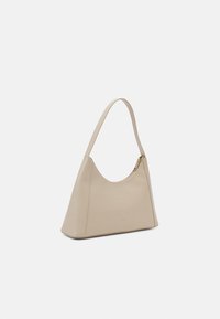 Beżowa skórzana torebka o zaokrąglonym kształcie, z pojedynczym regulowanym paskiem i zamkiem błyskawicznym. Gładka faktura i minimalistyczny design.