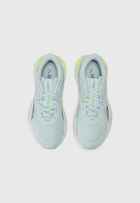 Világoskék sportcipők textúrált felsőrésszel, lime zöld díszítéssel, fehér talppal és fényvisszaverő részletekkel az oldalon és a fűzőn.