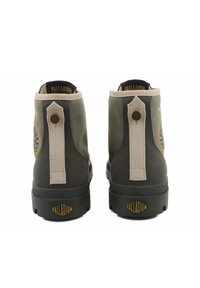 Bottines chelsea en toile verte et grise avec une semelle en caoutchouc noire, dotées d'un tirant en cuir beige et d'un logo circulaire sur le côté.