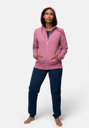 Roze zip-up hoodie met een capuchon, kangoeroezakken en geribbelde manchetten, gecombineerd met marineblauwe joggingbroeken van zachte stof.
