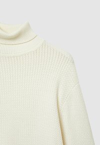 Cremfarbener Rollkragenpullover mit einem strukturierten, gerippten Muster und überschnittenen Schultern. Hergestellt aus weichem Strickmaterial.