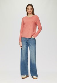 Rood en wit gestreepte langemouwen top met een ronde hals, gecombineerd met brede blauwe jeans en beige sneakers. Eenvoudig, casual ontwerp.