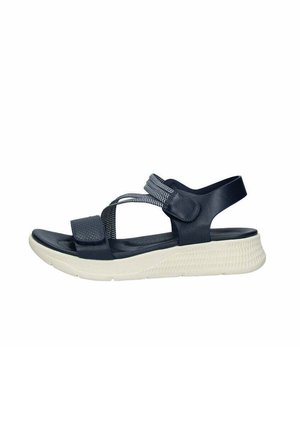 Sandali blu navy con tomaia testurizzata e cinturino elastico, dotati di suola bianca imbottita e chiusura regolabile in Velcro.