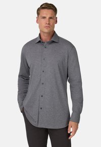 Graues langärmliges Button-up-Hemd aus weichem Stoff. Verfügt über einen Kragen und dunkle Knöpfe, mit einem leicht abgerundeten Saum und taillierter Passform.