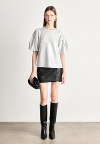 Hõbedane sädelev suur topp puhvvarrukatega, koos musta nahast mini seeliku ja mustade kõrge kontsaga terava ninaga saapadega. Hoidis musta käekotti.