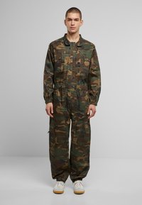 Zöld, barna és fekete álcázó overál, hosszú ujjakkal, elasztikus mandzsettákkal és derékkal, valamint több zsebbel a lábakon.