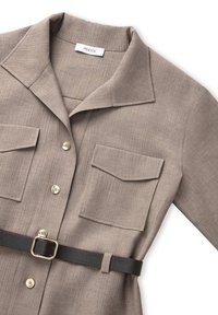 Beige overhemdjurk met kraag in een gemêleerde stof, voorzien van twee voorzakken, gouden knopen en een zwarte riem met een vierkante gesp.
