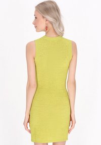 Abito verde senza maniche con un motivo testurizzato, design aderente e scollatura alta. La vista posteriore mostra una finitura liscia e una forma che abbraccia il corpo.