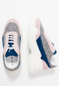 Baskets en feutre grises, roses et bleues avec une semelle blanche épaisse. Elles ont des lacets ronds et un col rembourré. Design épuré et moderne.