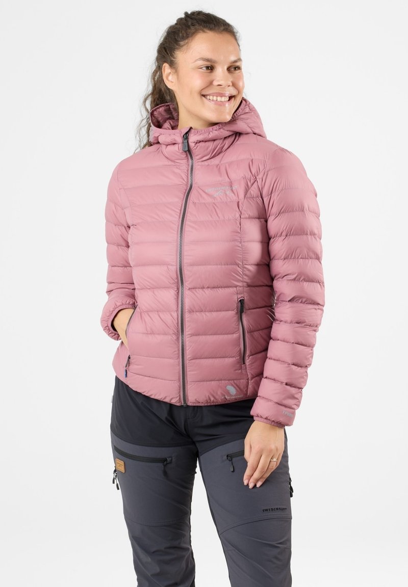 Giacca a vento rosa con cappuccio, dotata di una cerniera frontale, due tasche laterali e una texture liscia e trapuntata. Abbinata a pantaloni grigi scuri.