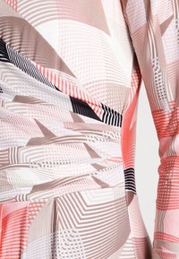 Wielokolorowa sukienka z geometrycznymi wzorami w odcieniach różu, beżu i czerni, o gładkiej fakturze i dopasowanym kroju.