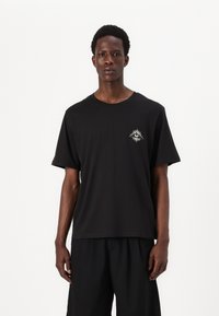 Black cotton t-shirt with a round neckline and short sleeves. Features an embroidered sun design on the left chest. Relaxed fit.