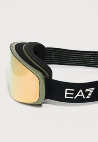 Lyžiarske okuliare so zlatou zahnutou šošovkou, olivovo zeleným rámom, čiernou penovou výplňou a čiernym elastickým pásikom s bielym logom "EA7".