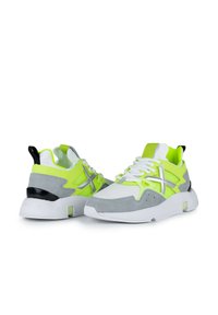 Zapatillas en verde lima y gris, con materiales de malla y ante, que presentan una suela blanca, detalles en plata y una pestaña en el talón negra.